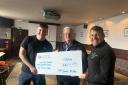 Jim and Devon accept the cheque from Jim Miller