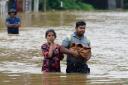 People wade through flood waters in Kelaniya, a suburb of Colombo, Sri Lanka (Eranga Jayawardena/AP)