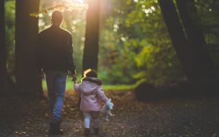 Father and daughter walking together in the woods. Credit: Canva